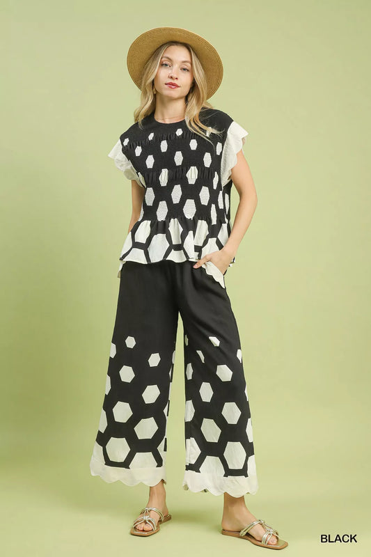 Woman wearing a black and white patterned outfit with a hat on a light green background