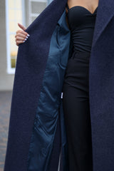 Person wearing a long navy coat with a satin lining, standing outdoors.