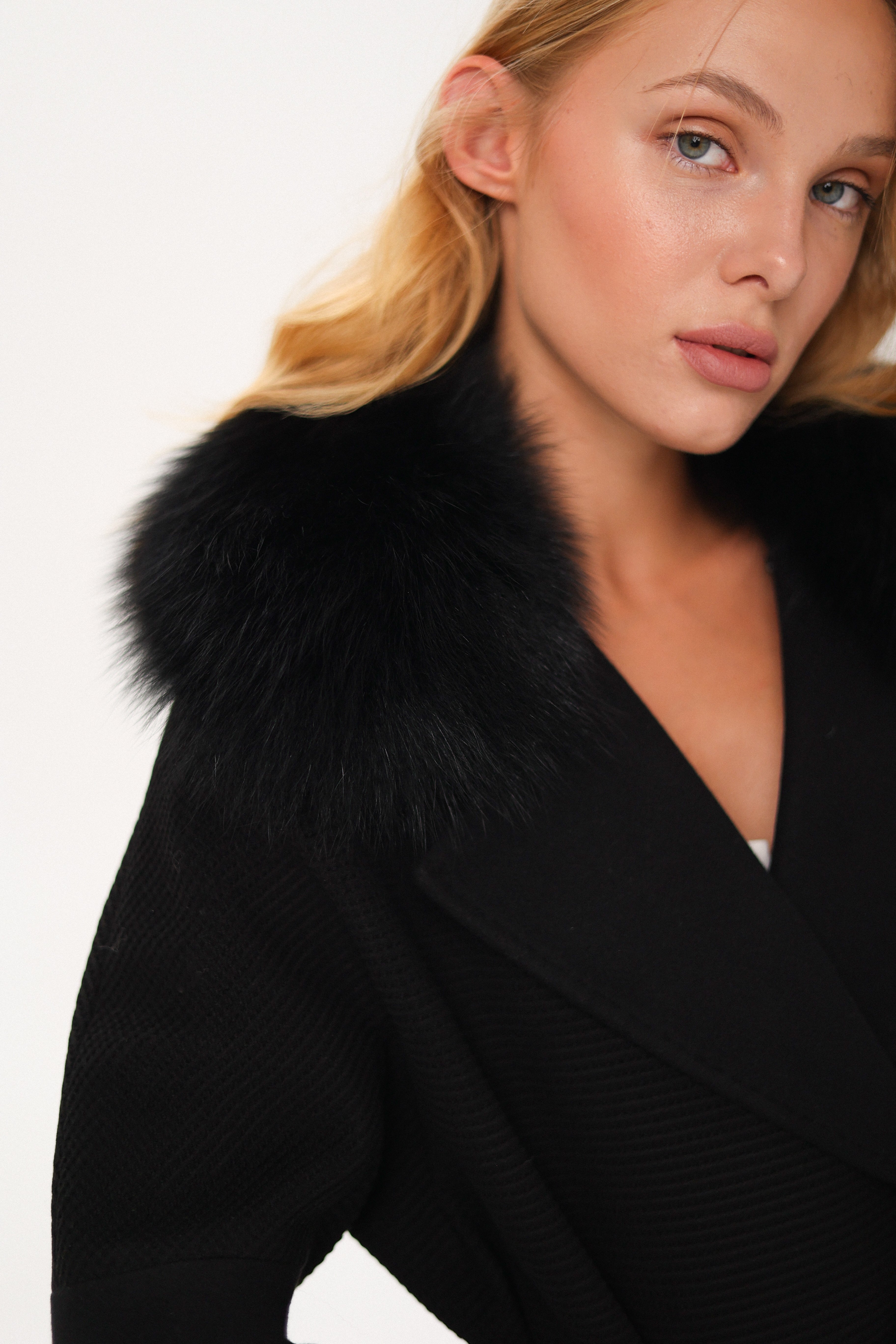Woman wearing a black coat with fur collar on a white background