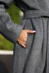 Gray coat with a person's hand in the pocket, blurred green background