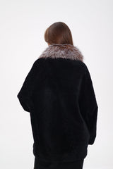 Person wearing a black coat with fur collar on a white background