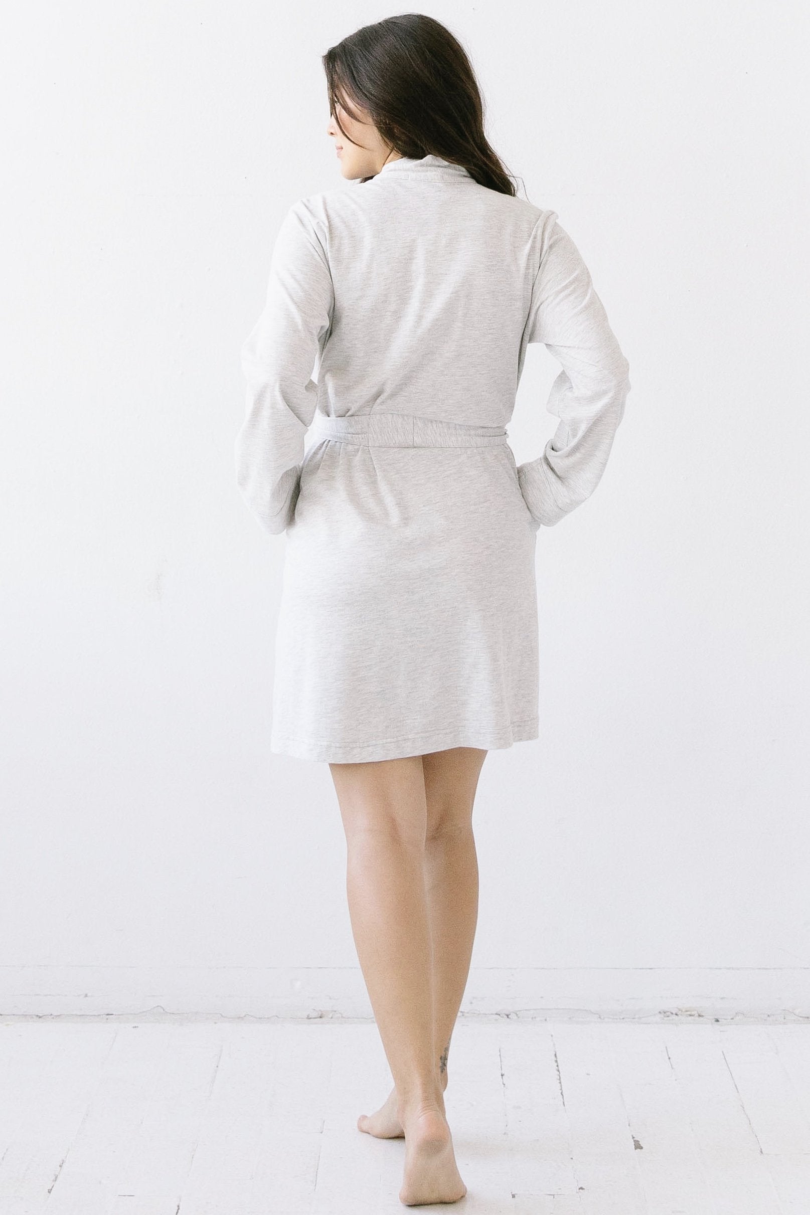 Woman wearing a light gray robe against a white background