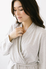 Woman wearing a light gray robe against a white background