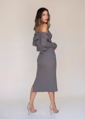 Woman wearing a gray off-shoulder top and skirt set against a plain background
