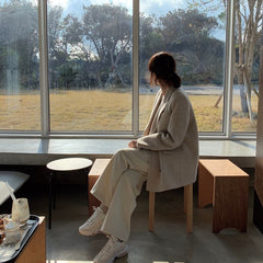 Person sitting in a modern cafe looking out large windows at a park.