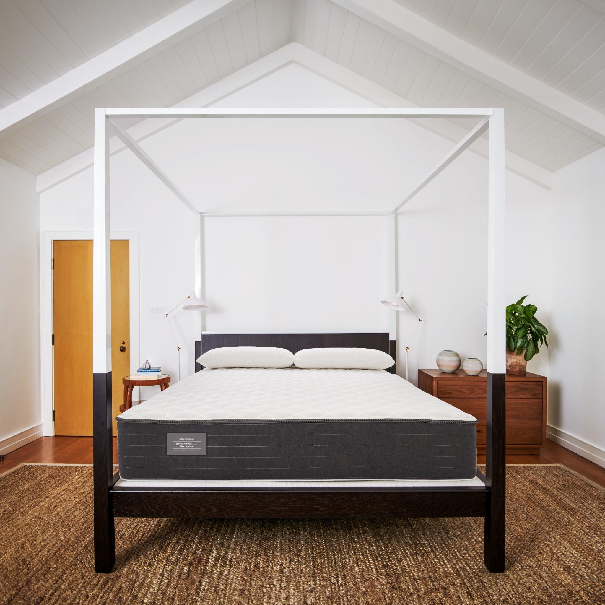 Bed with a mattress in a room with wooden floors and white walls