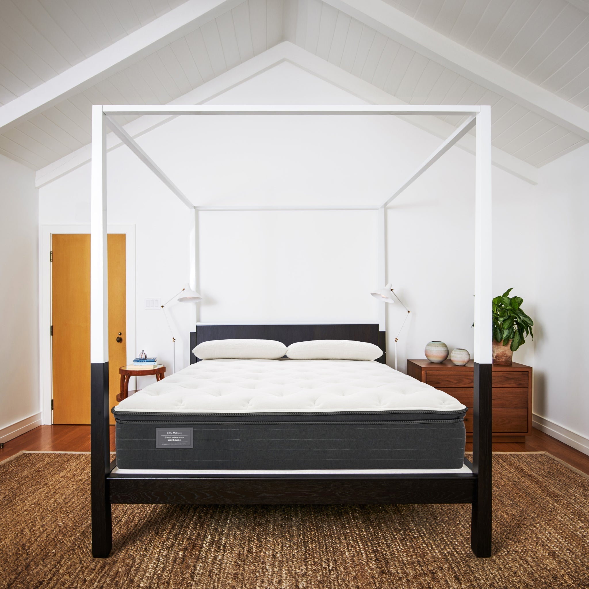 Bed with a mattress in a room with wooden floors and white walls.