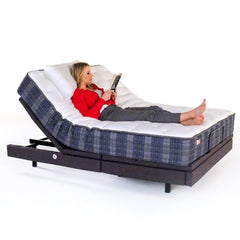 Woman lying on a adjustable bed with blue and white plaid pattern, using a tablet.