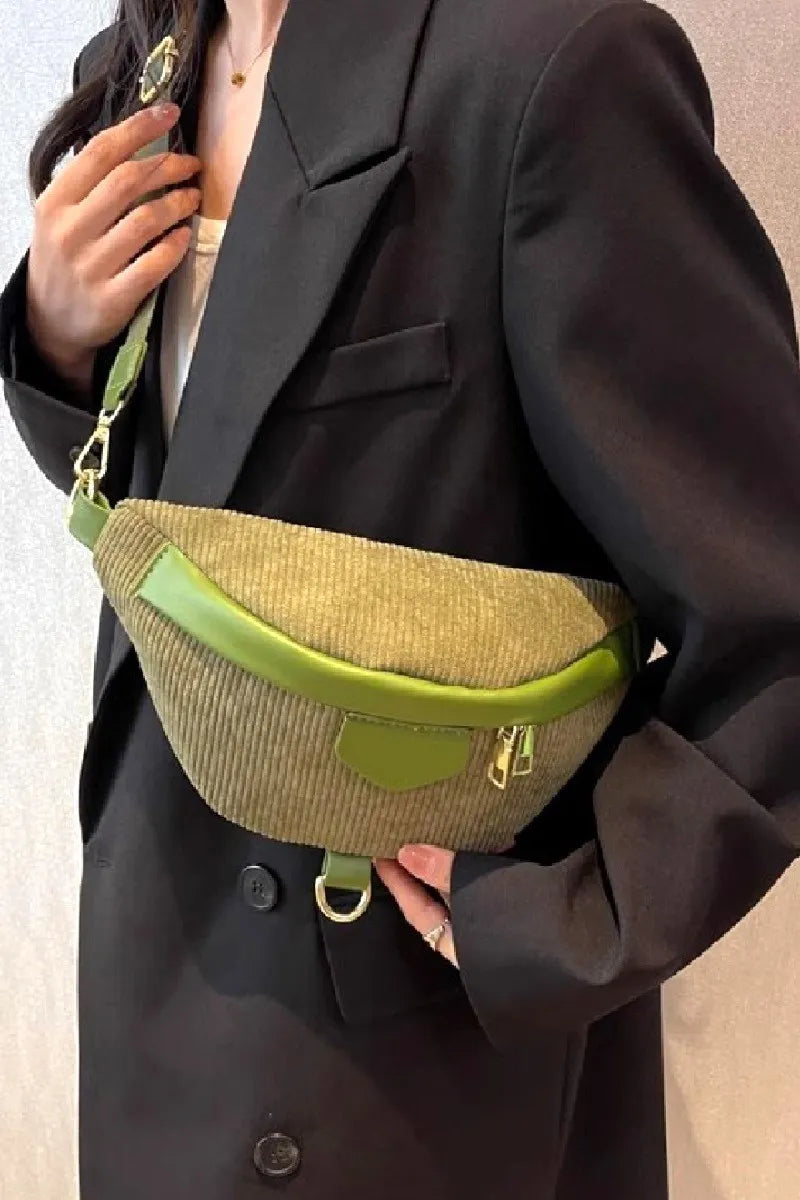 Person wearing a dark coat holding a green and beige bag.