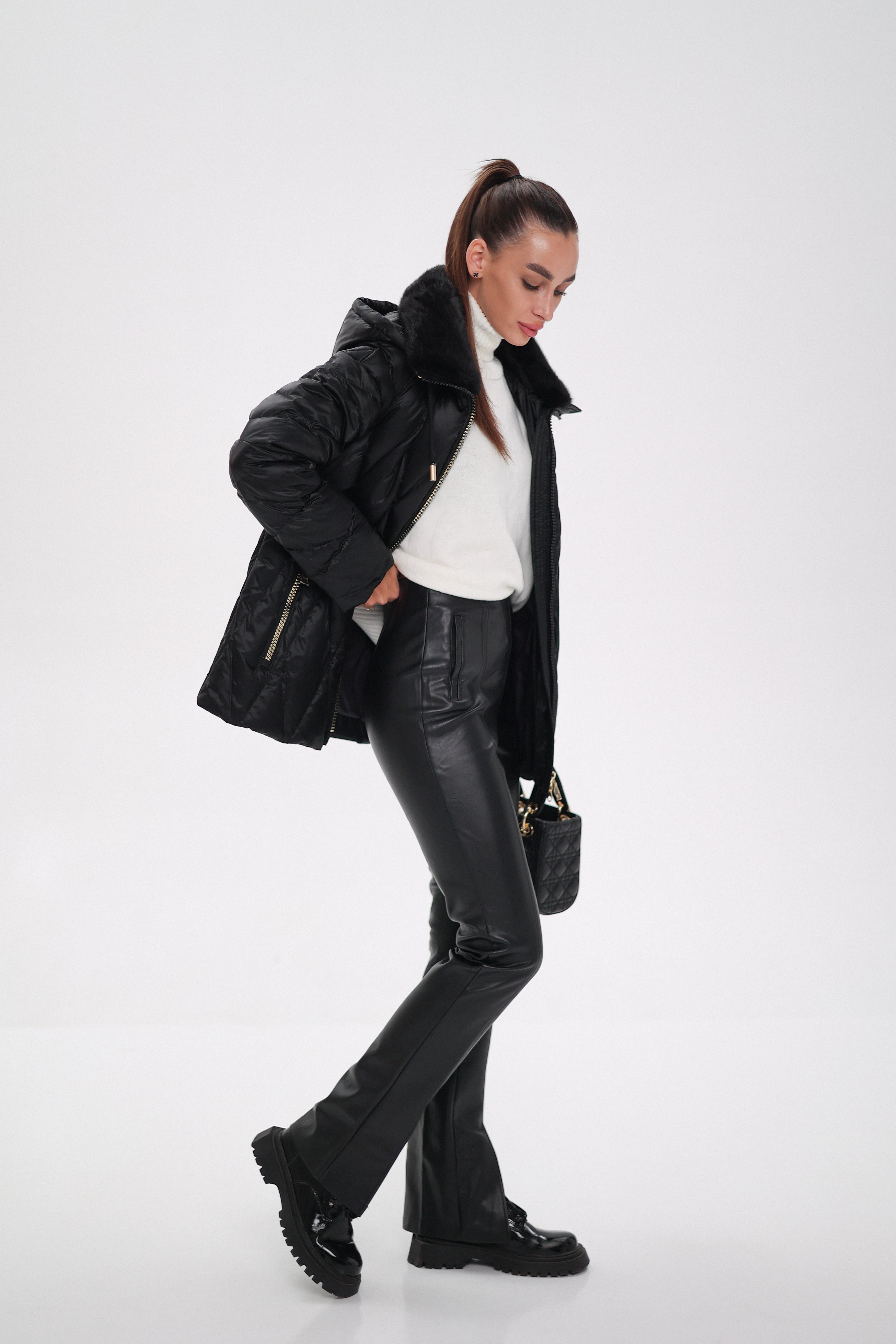 Person wearing a black puffer jacket, black pants, and black shoes on a white background