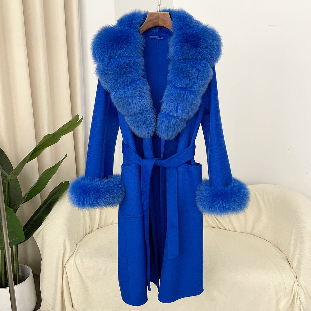 Blue coat with fur trim on a chair against a white curtain background