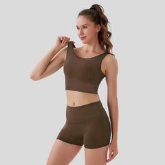 Woman wearing a brown sports bra and shorts set on a light gray background