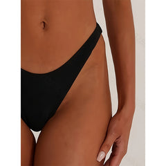 Black bikini bottom worn by a person on a neutral background