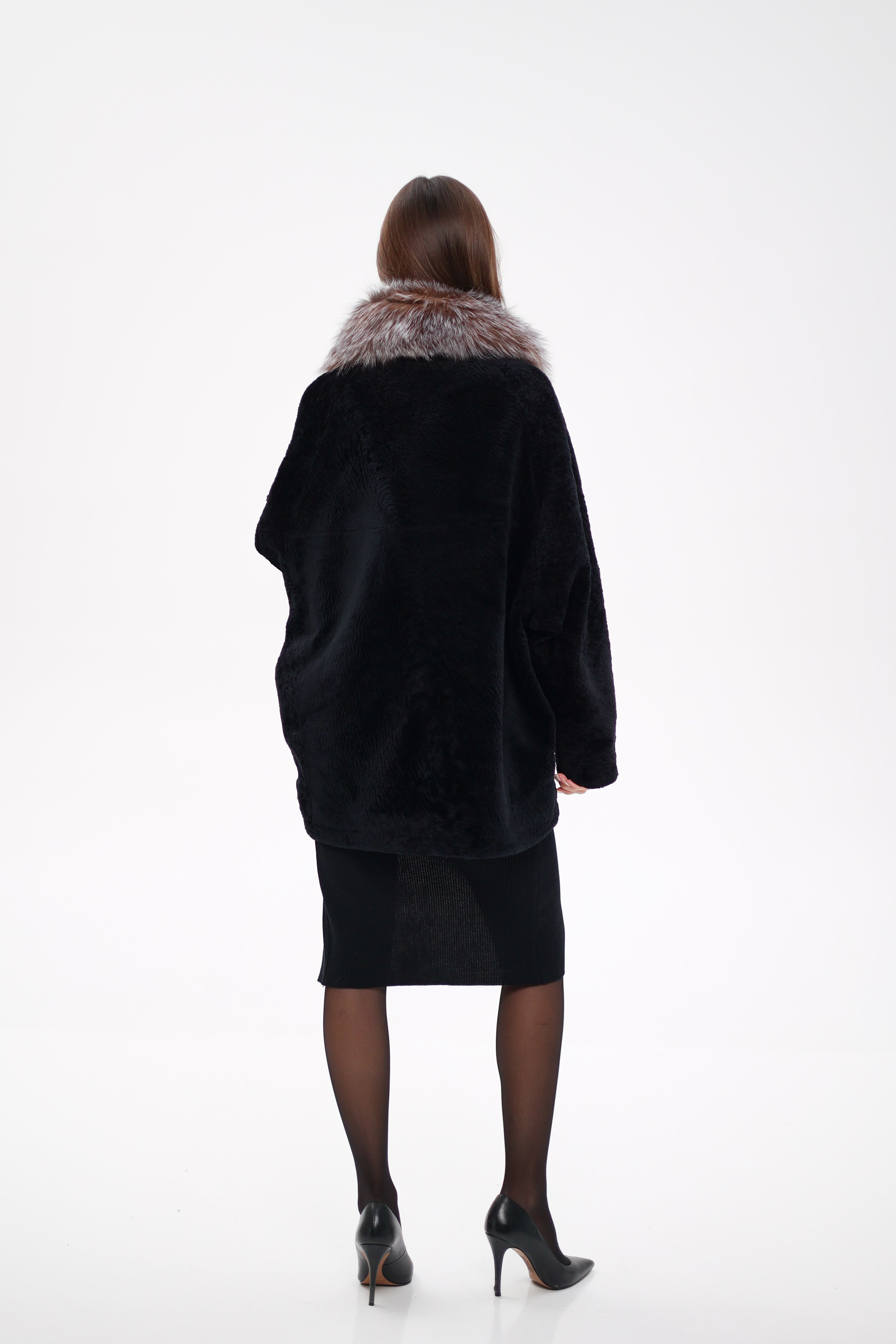 Person wearing a black coat with fur trim on a white background