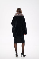 Person wearing a black coat with fur trim on a white background