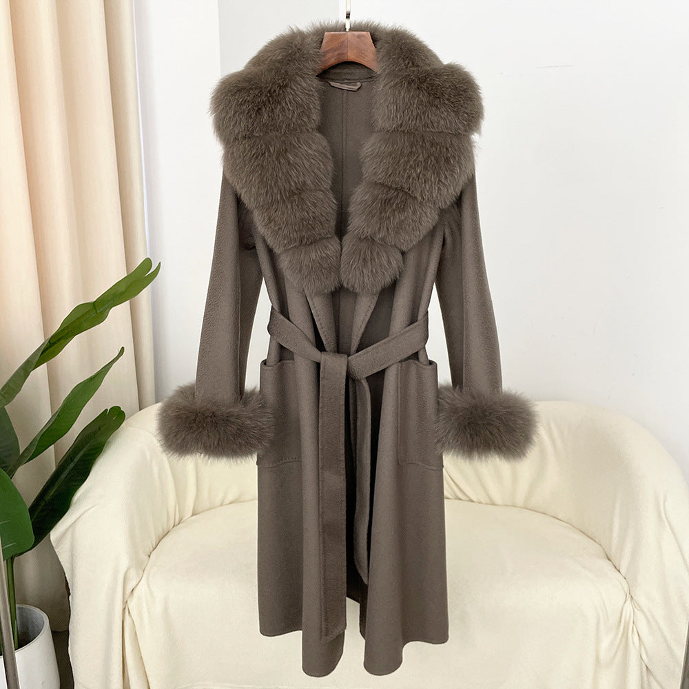 Gray coat with fur trim hanging on a chair against a white wall.