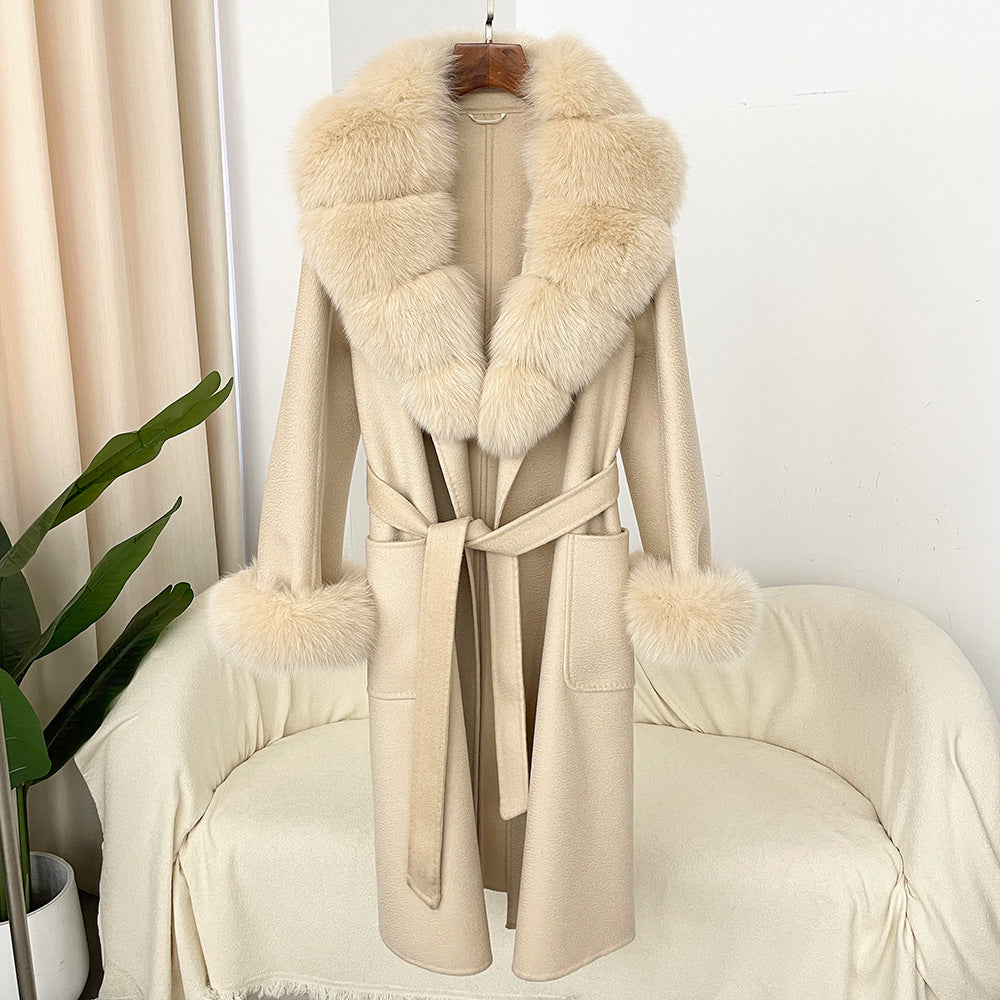 Beige coat with fur collar and cuffs on a chair against a white wall