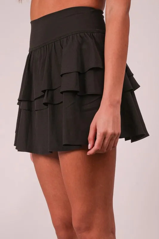 Black ruffled skirt worn by a person on a plain background