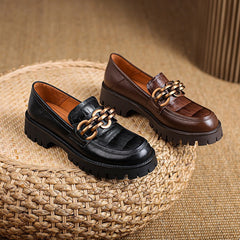 Black and brown loafers with gold accents on a woven surface