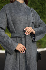 Person wearing a gray coat with a blurred green background