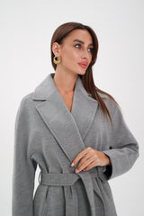 Woman wearing a gray coat over a black outfit on a white background