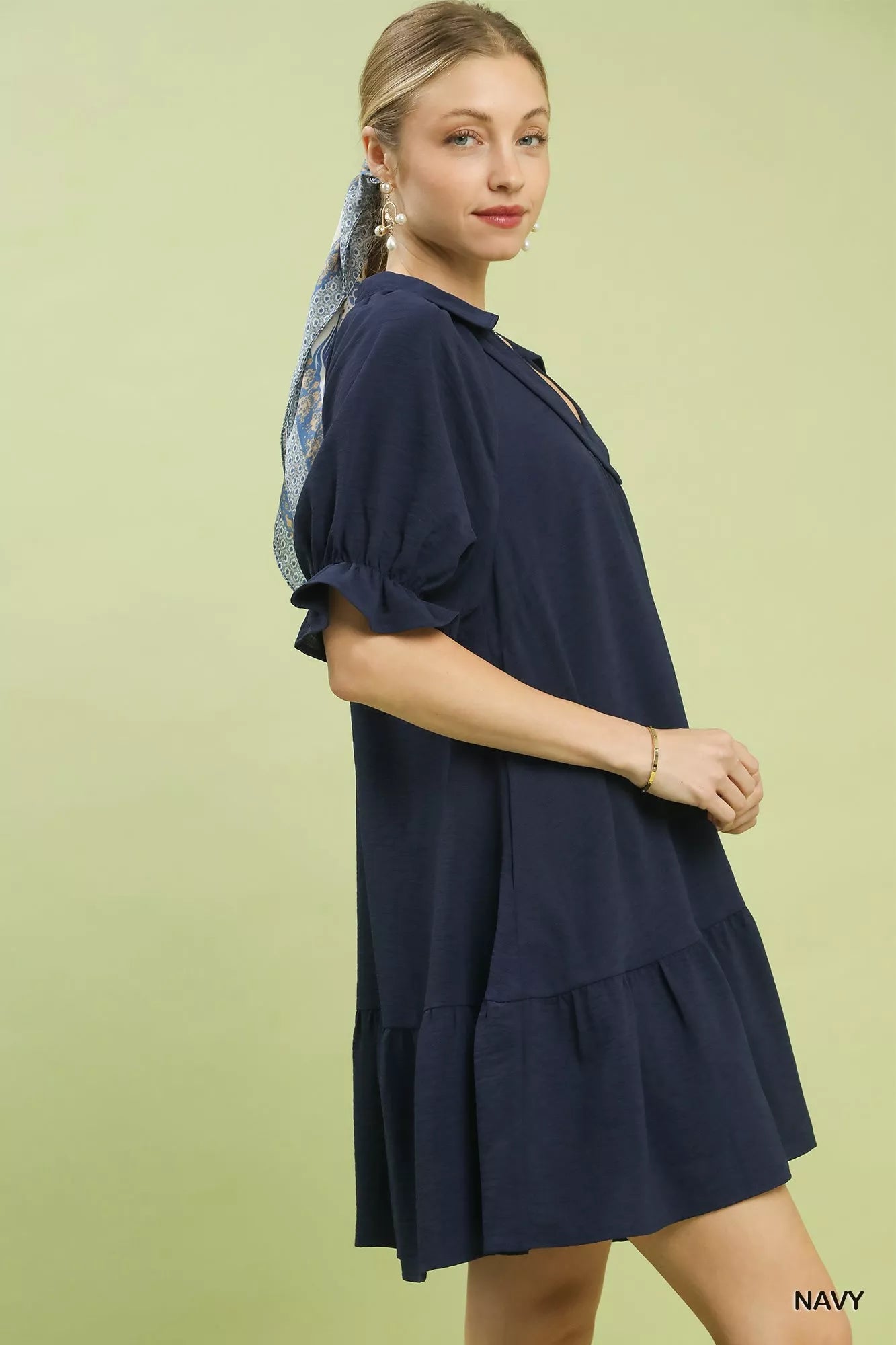 Woman wearing a navy dress on a light green background