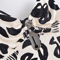 Close-up of a black and white patterned fabric with a bow and button on a light gray background