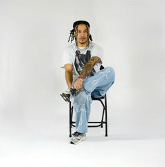 Person sitting on a chair wearing a white t-shirt, blue jeans, and black shoes against a white background