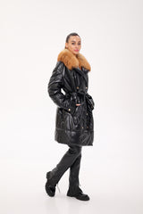 Person wearing a black coat with fur trim on a white background