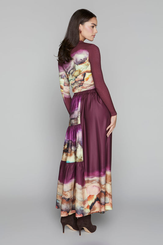 Woman wearing a long, burgundy dress with floral patterns on a gray background