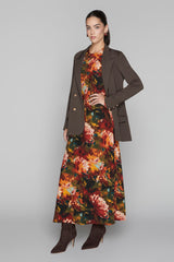Woman wearing a floral dress with a brown coat on a gray background