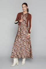 Woman wearing a patterned dress with a brown cardigan on a gray background