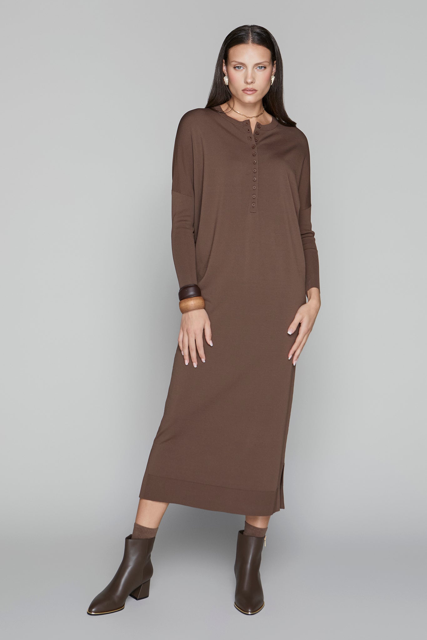 Woman wearing a brown dress and boots on a gray background