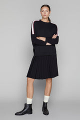 Woman wearing a black outfit with white accents on a gray background