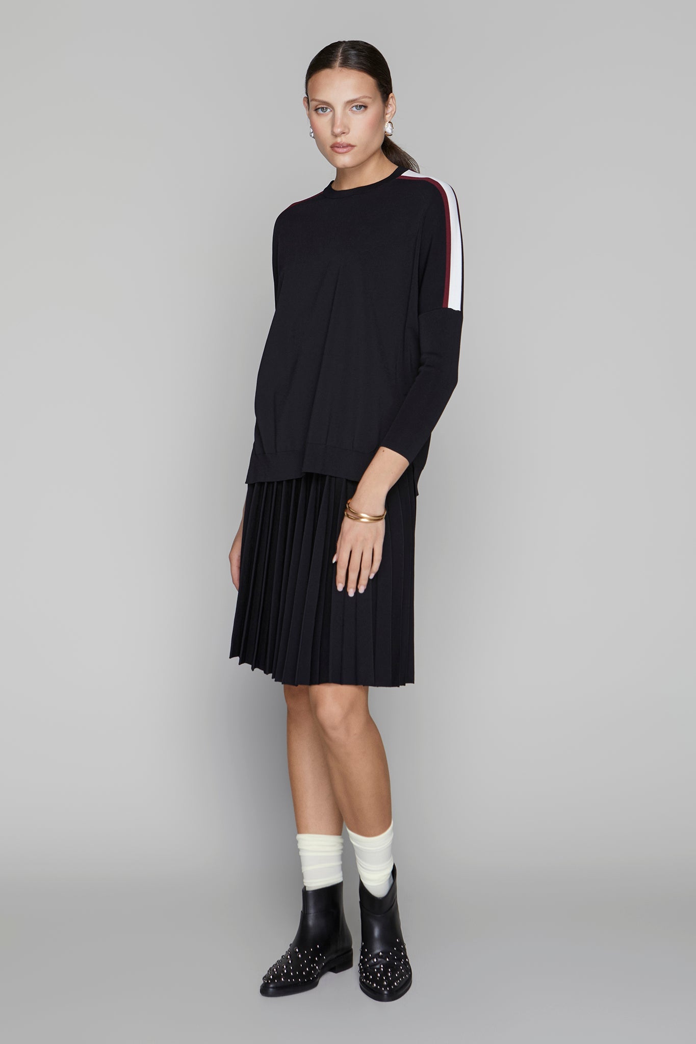Woman wearing a black outfit with white accents on a gray background