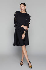 Woman wearing a black dress with decorative sleeves on a gray background