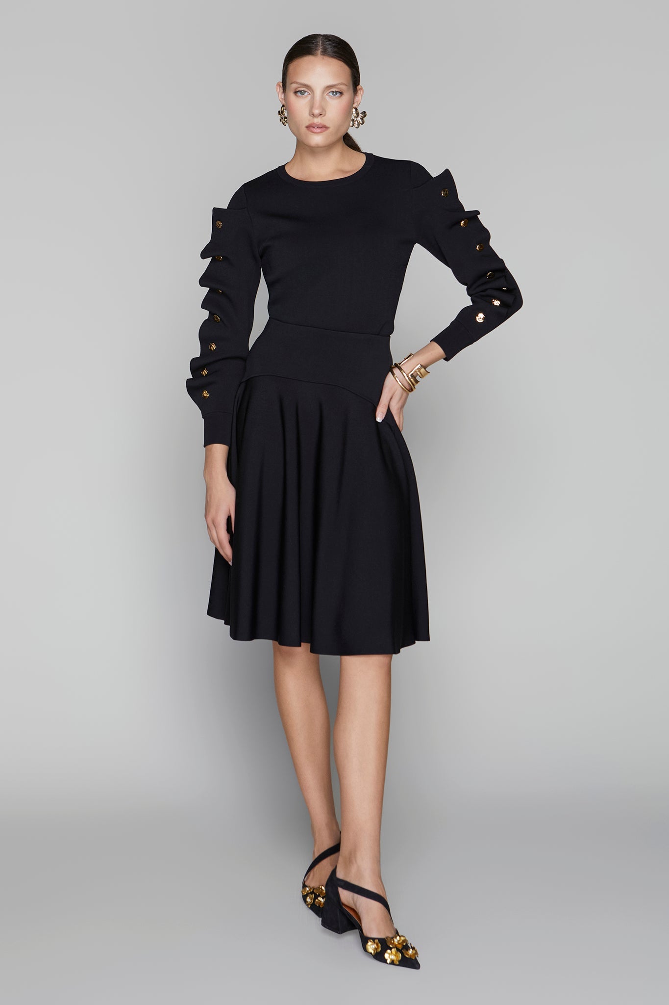 Woman wearing a black dress with ruffled sleeves on a gray background