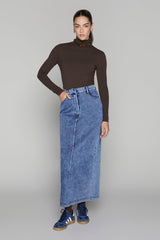 Woman wearing a brown turtleneck and blue denim skirt on a gray background