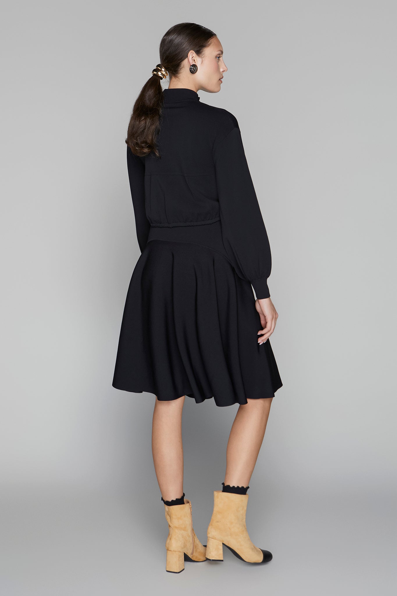 Woman wearing a black outfit with yellow boots on a gray background