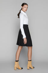 Woman wearing a white shirt, black skirt, and yellow boots on a gray background