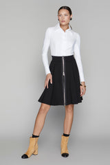 Woman wearing a white shirt and black skirt with a zipper on a gray background