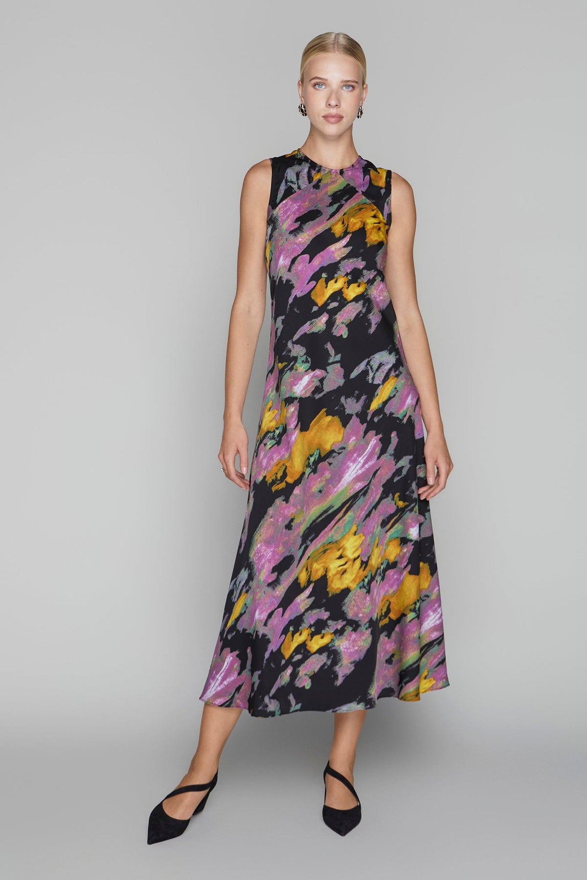 Woman wearing a sleeveless dress with colorful abstract pattern on a gray background
