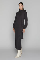 Woman wearing a black dress with a high collar and long sleeves on a gray background