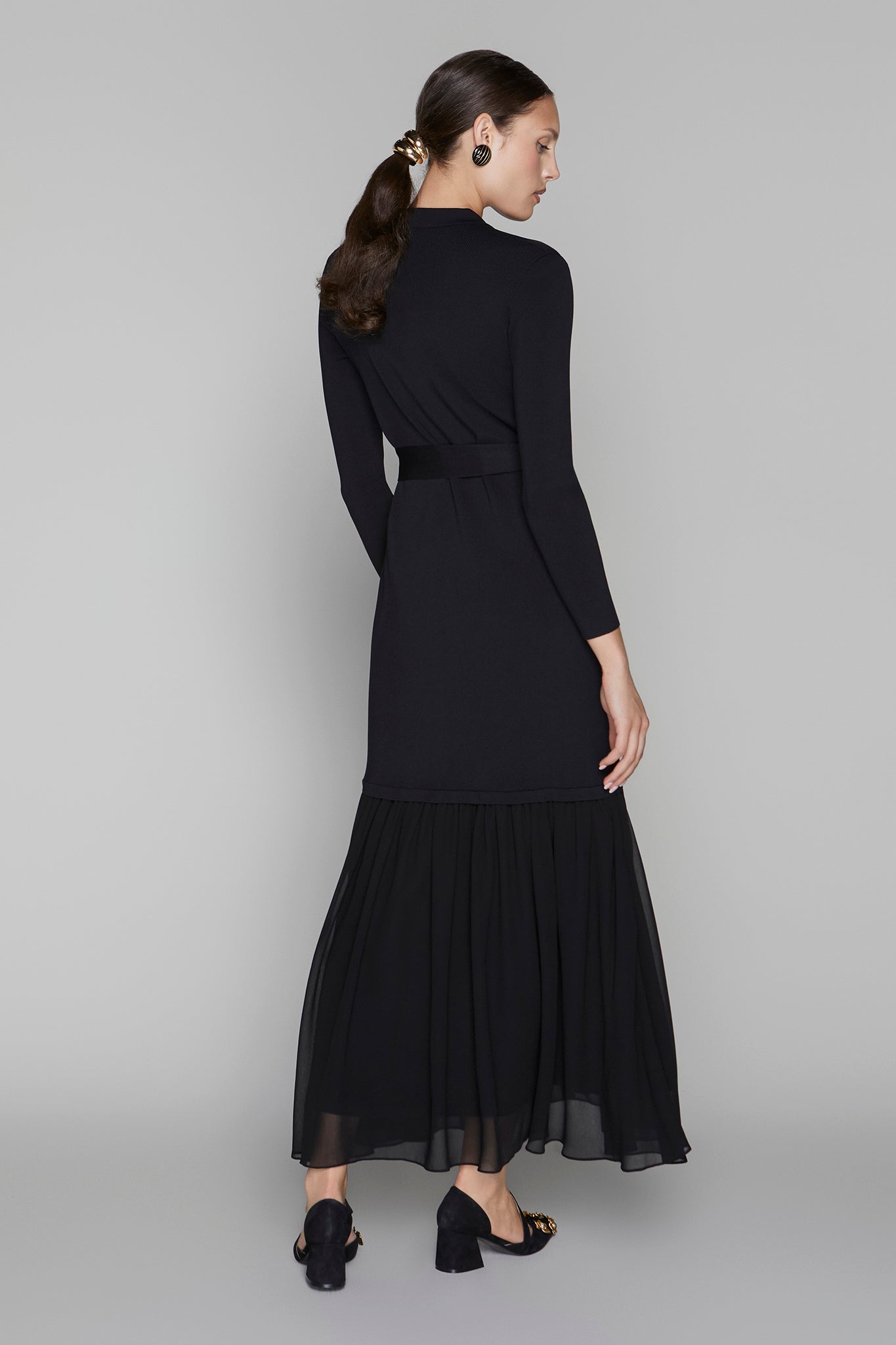 Woman wearing a black dress with a belt on a gray background
