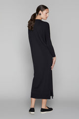 Woman wearing a black long-sleeve dress against a gray background