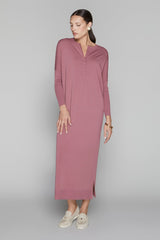 Woman wearing a long mauve dress on a gray background