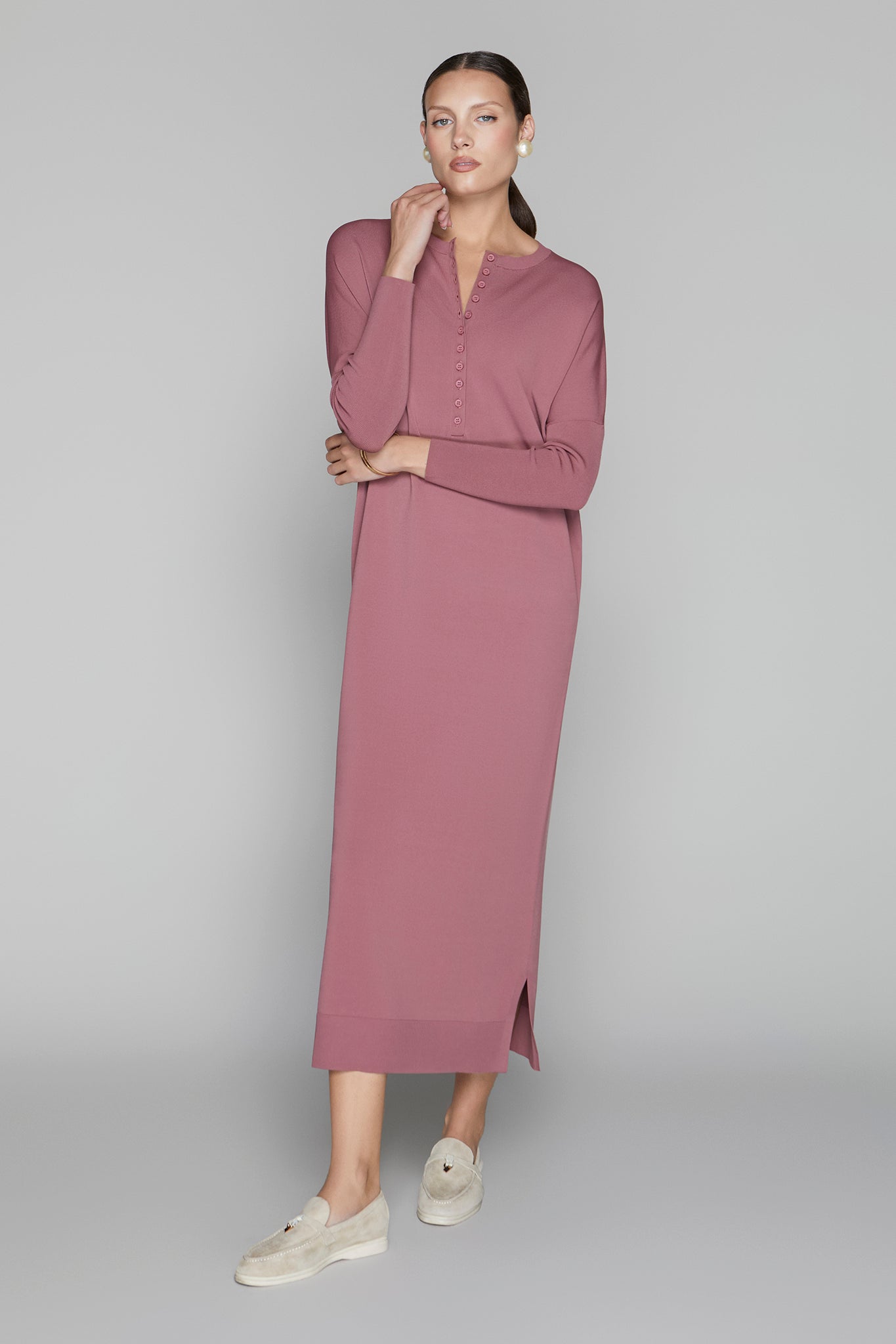 Woman wearing a long mauve dress on a gray background