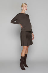 Woman wearing a brown sweater and skirt with matching knee-high boots on a gray background