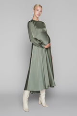 Woman wearing a green dress and white boots on a gray background
