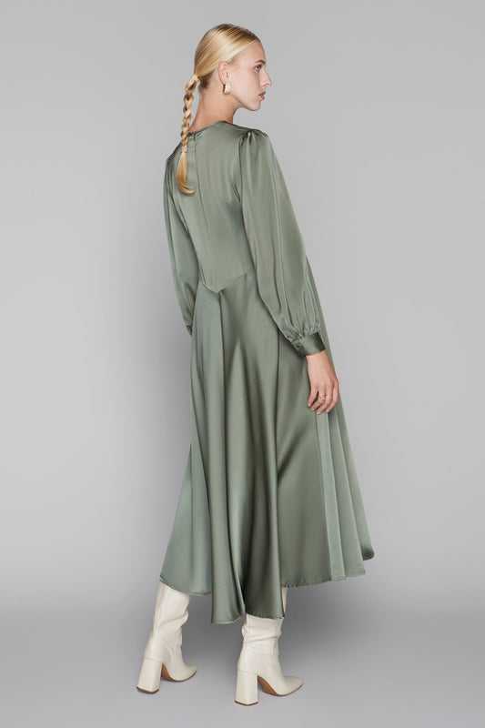 Woman wearing a green dress with long sleeves and a plain background